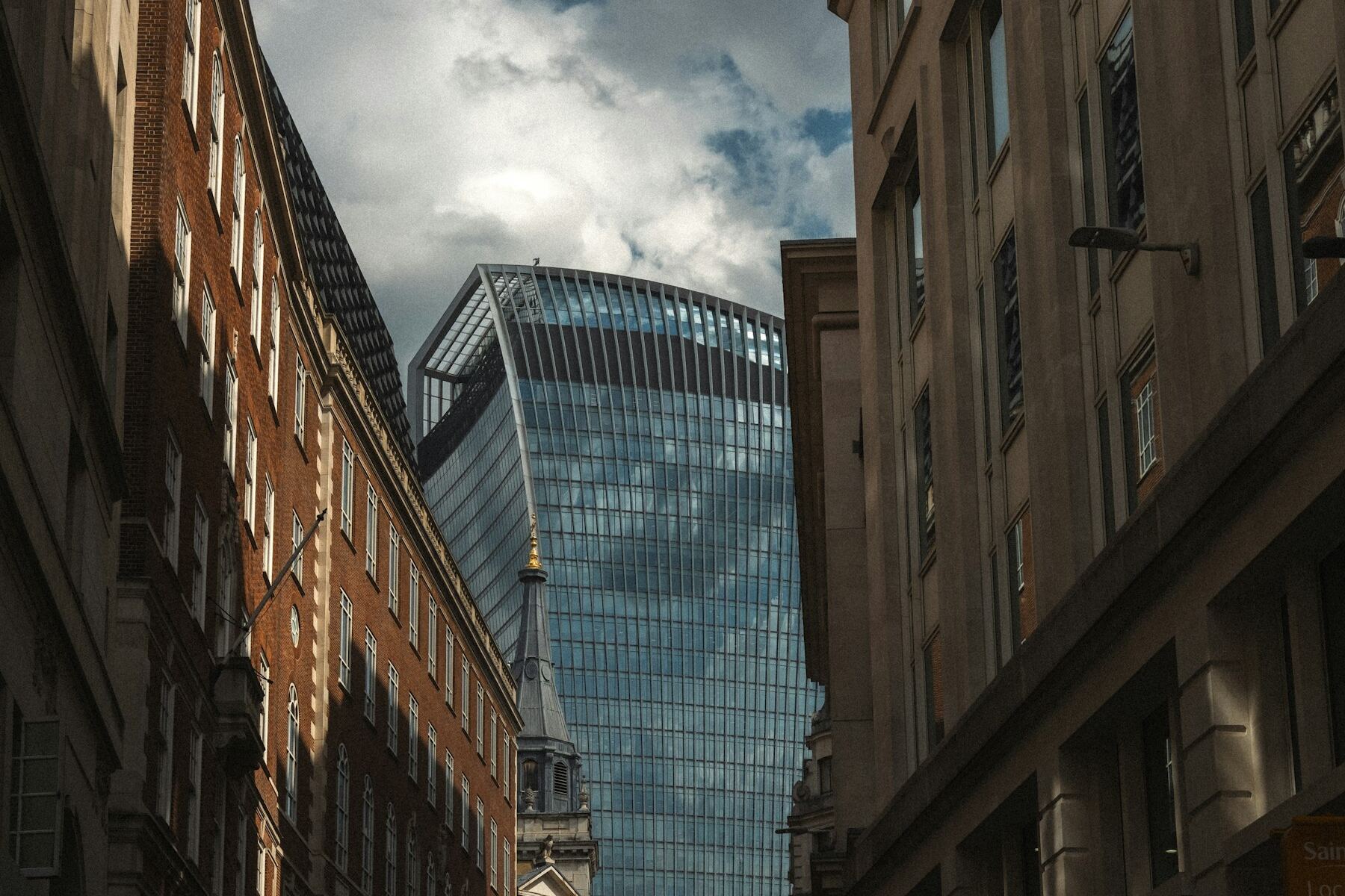 Older City of London street buildings with a modern glass office tower rising behind them